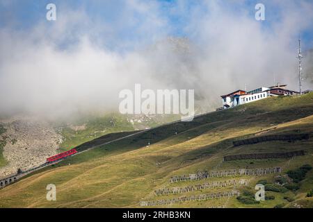 Funiculaire rouge dans les alpes suisses, couvert de nuages, dans la station estivale Davos, Suisse. Banque D'Images