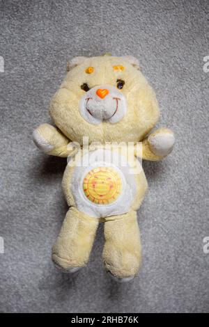 Funshine Care, peluche Care Bear des années 1980, sur un tapis gris. Banque D'Images