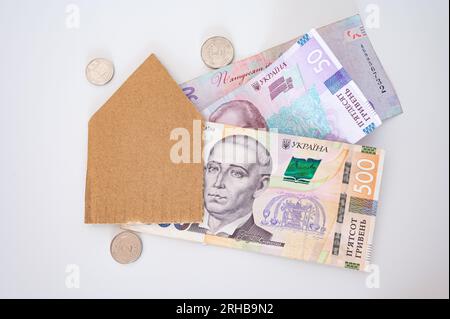 Argent ukrainien, pièces de monnaie et maison de papier sur le fond blanc. Pour le financement, l'économie, le logement, le mortage, le coût de la vie, Ukraine Banque D'Images