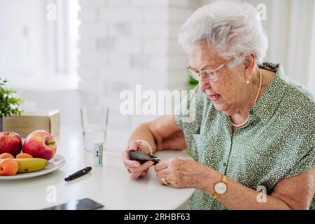 Patiente diabétique âgée vérifiant son taux de sucre dans le sang avec un glucomètre. Banque D'Images