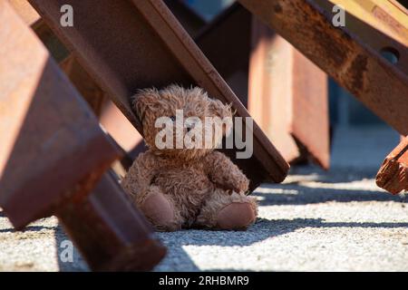 Un ours en peluche se trouve à côté d'un hérisson antichar sur une route dans la ville de Dnipro en Ukraine pendant la guerre Banque D'Images