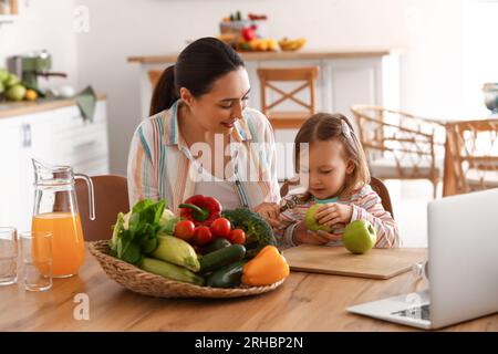 Petite fille avec sa mère épluchant la pomme dans la cuisine Banque D'Images