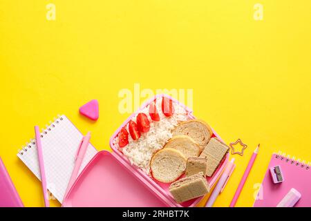 Lunchbox avec de la nourriture délicieuse et de la papeterie différente sur fond jaune Banque D'Images