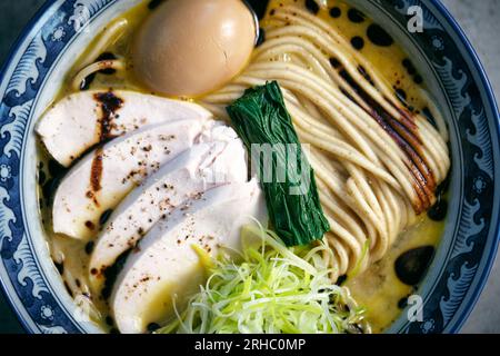 Vue de dessus de la savoureuse soupe de nouilles japonaises avec des œufs durs et des légumes frais dans un bouillon avec une sauce de soja dans un bol Banque D'Images