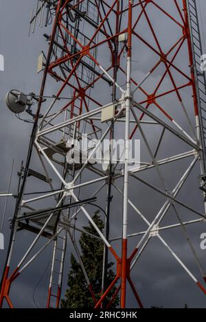 Tour métallique de télécommunications peinte en blanc et rouge avec escaliers et plates-formes d'accès à plusieurs antennes Banque D'Images