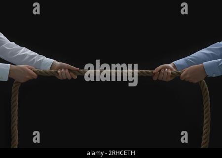 Concept de litige. Hommes tirant la corde sur fond noir, closeup Banque D'Images