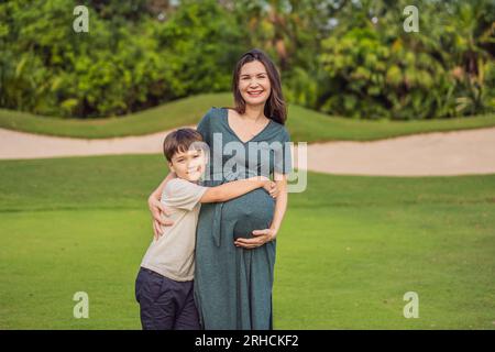 Un moment réconfortant capturé dans le parc alors qu'une femme enceinte après 40 partage un lien spécial avec son fils adolescent, embrassant la beauté de la mère Banque D'Images