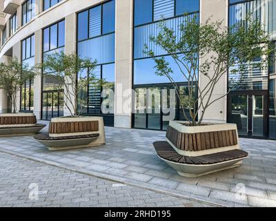 cour dans un complexe d'immeubles de bureaux avec des arbres verts et des bancs pour le repos. Banque D'Images