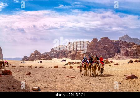 Wadi Rum, Jordanie - 15 avril 2023: Les touristes apprécient une promenade avec des chameaux dans le désert. Banque D'Images