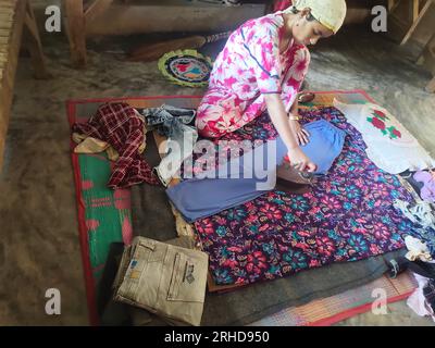 Une femme repassant avec un vieux fer à charbon de bois au camp de réfugiés de Balukhali. Environ 919 000 000 réfugiés Rohingyas vivent dans les camps de Kutupalong et de Nayapara dans la région de Cox’s Bazar, qui sont devenus l’un des camps les plus vastes et les plus densément peuplés au monde. Bangladesh. Banque D'Images