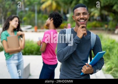 Bel étudiant masculin afro-américain avec groupe de jeunes adultes féminins brésiliens en plein air dans la ville tropicale Banque D'Images