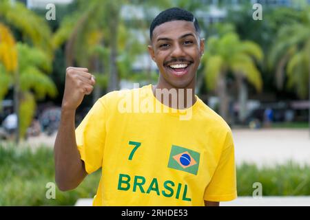 Heureux jeune homme du Brésil avec maillot de football jaune en plein air à Sao Paulo Banque D'Images