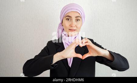 Femme musulmane dans le hijab avec l'expression souriante fait coeur Banque D'Images