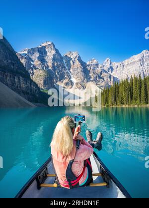 Femme prenant un selfie dans un canoë, lac Moraine pendant l'été dans le parc national Banff, Rocheuses canadiennes, Alberta, Canada. Parc national Banff, Alberta Banque D'Images