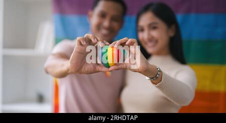 Un animateur de radio gay asiatique charmant et joyeux aime bavarder tout en enregistrant un podcast audio avec son amie avec un drapeau arc-en-ciel dans le Banque D'Images