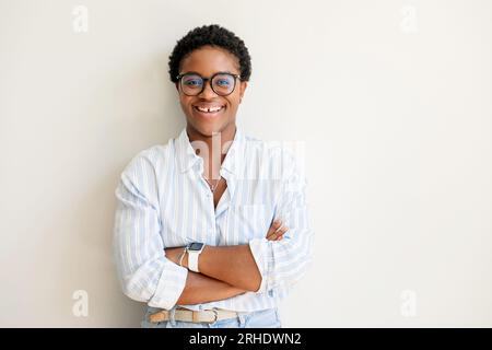 Femme afro-américaine réussie debout dans la pose confiante avec les bras croisés et regardant la caméra isolée sur blanc, joyeuse femme entrepreneur avec coupe de cheveux courte, freelance, femme d'affaires Banque D'Images