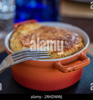 Soufflé aux œufs français dans un pot rouge avec fourchette au restaurant Banque D'Images