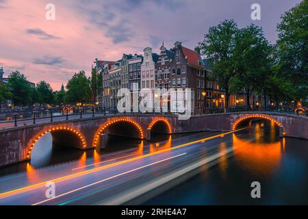 Une soirée d'été avec la vue sur le coin du Keizersgracht et Leidsegracht withun canalboat passe sous le pont dans le centre-ville d'Amsterda Banque D'Images