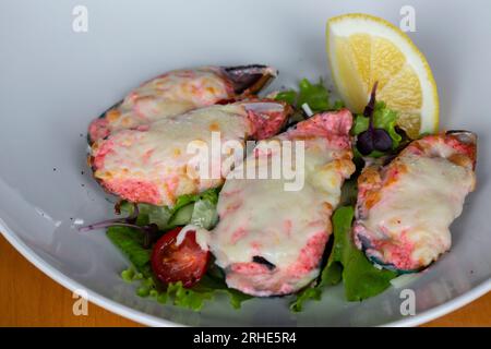moules cuites au four avec du caviar masago et du fromage sur une assiette blanche avec du citron Banque D'Images