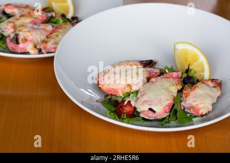 moules cuites au four avec du caviar masago et du fromage sur une assiette blanche avec du citron Banque D'Images