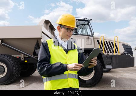 Homme travailleur avec tablette ordinateur se tient à côté du camion minier.. Banque D'Images