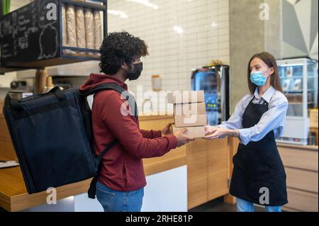 Courrier masculin aux cheveux bouclés prenant les ordres du café Banque D'Images