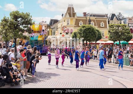 Défilé de Disneyland Paris, avec des danseurs dansant dans main Street, et les visiteurs regardant le défilé Disney, en été ; France Europe Banque D'Images