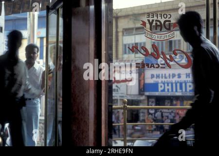 Un Cyber café sur une route avec des magasins et de la circulation dans la ville de Bangalore dans la province Karnataka en Inde. Inde, Bangalore, avril 1998 Banque D'Images