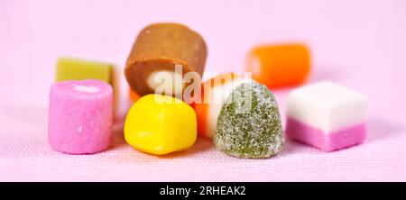 Gros plan panoramique de bonbons de mélange dolly sur rose Banque D'Images