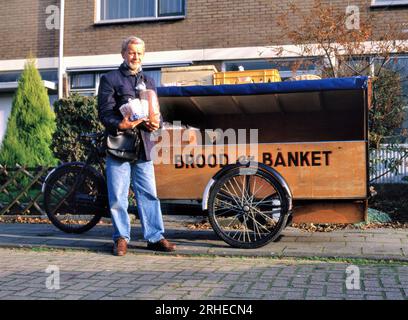 MAASDIJK, HOLLANDE- 01 AVRIL 2021 : chariot de livraison de pain à l'ancienne avec le boulanger dans une rue d'un quartier résidentiel. Au panier est écrit en néerlandais Banque D'Images