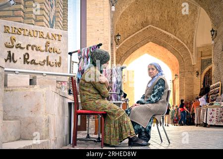 Deux femmes ouzbèkes assises et parlant dans les rues de la vieille ville de Boukhara, Ouzbékistan Banque D'Images