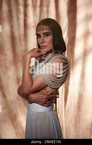 Femme Brunette dans la coiffe égyptienne traditionnelle et le regard posant sur fond abstrait Banque D'Images