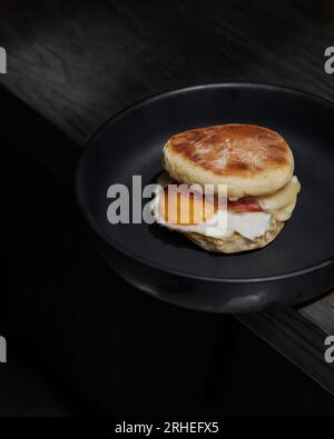 sandwich aux œufs avec du pain maison épais, sont du bacon, de la nourriture salée sur fond noir de plaque en céramique noire Banque D'Images