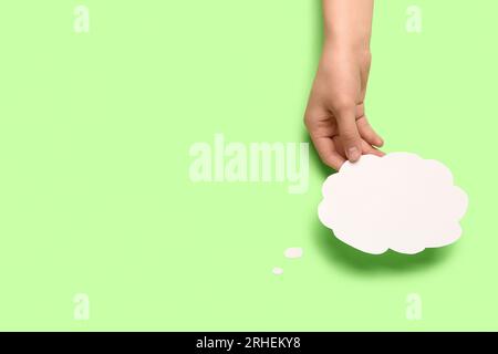 Femme tenant une bulle de parole vide sur fond vert Banque D'Images