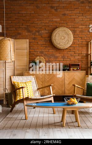 Fauteuil en bois confortable avec coussin et panier de fruits sur planche de surf à l'intérieur du salon Banque D'Images