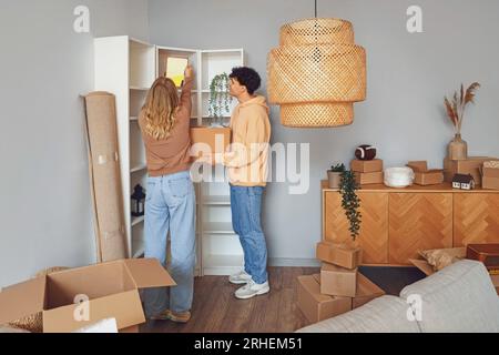 Jeune couple emballer miroir dans la chambre le jour du déménagement Banque D'Images