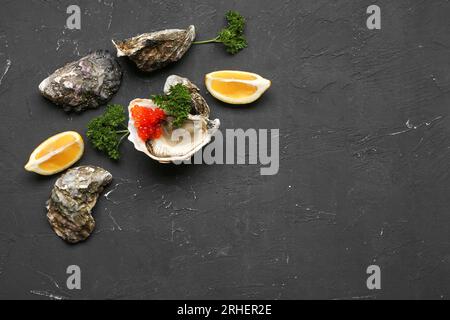 Huîtres savoureuses au citron et caviar rouge sur fond noir Banque D'Images