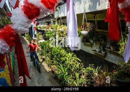 Bandung, Indonésie. 16 août 2023. Un enfant traverse à vélo la décoration en tissu rouge et blanc qui orne une ruelle à Cikudapateh Dalam, Bandung, Java Ouest, Indonésie le mardi 16 janvier, 2023. les ornements et décorations des résidents de cette colonie densément peuplée commémorent le 78 août le 17 août le cinquantième anniversaire de l ' indépendance de la République d ' Indonésie. (Photo Dimas Rachmatsyah/INA photo Agency/Sipa USA) crédit : SIPA USA/Alamy Live News Banque D'Images