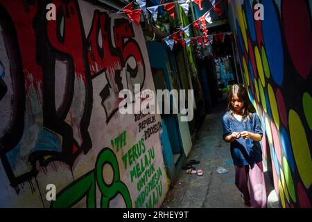 Bandung, Indonésie. 16 août 2023. Un enfant marche à travers le mur mural de l'année 1945 de l'indépendance indonésienne qui orne une ruelle à Cikudapateh Dalam, Bandung, Java Ouest, Indonésie le mardi 16 janvier, 2023. les ornements et décorations des habitants de cette colonie densément peuplée commémorent le 78e anniversaire de l ' indépendance de la République d ' Indonésie, le 17 août. (Photo Dimas Rachmatsyah/INA photo Agency/Sipa USA) crédit : SIPA USA/Alamy Live News Banque D'Images