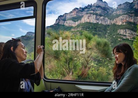 Touristes asiatiques à l'intérieur du train de chemin de fer crémallera à crémaillère qui monte la montagne de Montserrat, Monistrol de Montserrat, Barcelone, Espagne. Le Montserrat r Banque D'Images