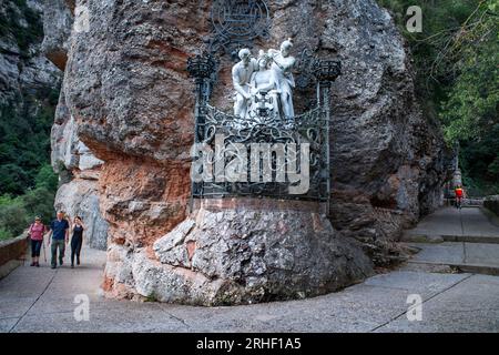 Statue blanche du christ avec couronne d'épines, soldat romain, une autre figure et ferronnerie avec croix sur le chemin de santa cova chapelle sur la montagne M. Banque D'Images