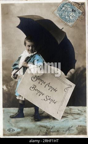 Carte de voeux de bonne annee : un enfant s'abritant sous une parapluie - carte postale fin 19e-20e siecle Banque D'Images