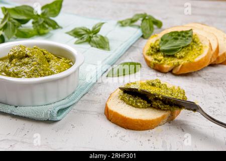 Une photo de tartiner du pesto frais sur de petites tranches de pain dans un studio. Banque D'Images