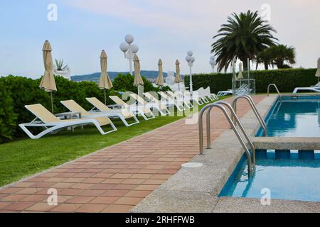 Chaises longues vides à côté de la piscine dans la lumière du soir à l'Hôtel Louxo hôtel de luxe 4 étoiles la Toja Island Pontevedra Galice Espagne Banque D'Images