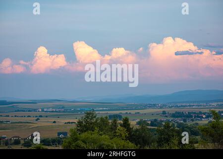 Distant storm clouds over the hilly landscape in northern Slovakia are illuminated pink by the setting sun Stock Photo