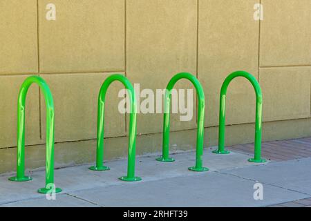 Ensemble de porte-vélos en U tubulaire inversé vert de couleur vive sur le trottoir par le mur jaune dans le centre-ville de Las Cruces Nouveau-Mexique Banque D'Images