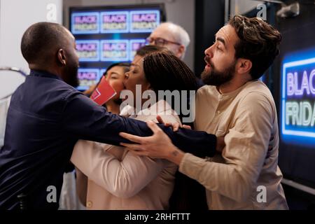 Des acheteurs fous en colère se battent pour de bonnes affaires, une foule de personnes folles et frénétiques poussant des gardes de sécurité et se bousculant pendant les soldes du Black Friday, essayant d'être les premiers en magasin et d'obtenir les meilleures offres Banque D'Images