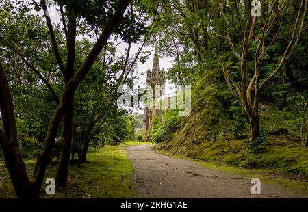 Chemin dans le jardin (Mata Jose do Canto) avec la chapelle Nossa Senhora das Vitorias en arrière-plan. Lac de Furnas. Açores, Sao Miguel Island. Banque D'Images