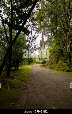 Chemin dans le jardin (Mata Jose do Canto) avec la chapelle Nossa Senhora das Vitorias en arrière-plan. Lac de Furnas. Açores, Sao Miguel Island. Banque D'Images