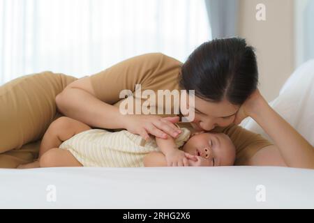 La mère asiatique a embrassé son jeune fils pour qu'elle puisse avoir un bon sommeil dans la chambre à la maison, représente l'amour et la famille Banque D'Images